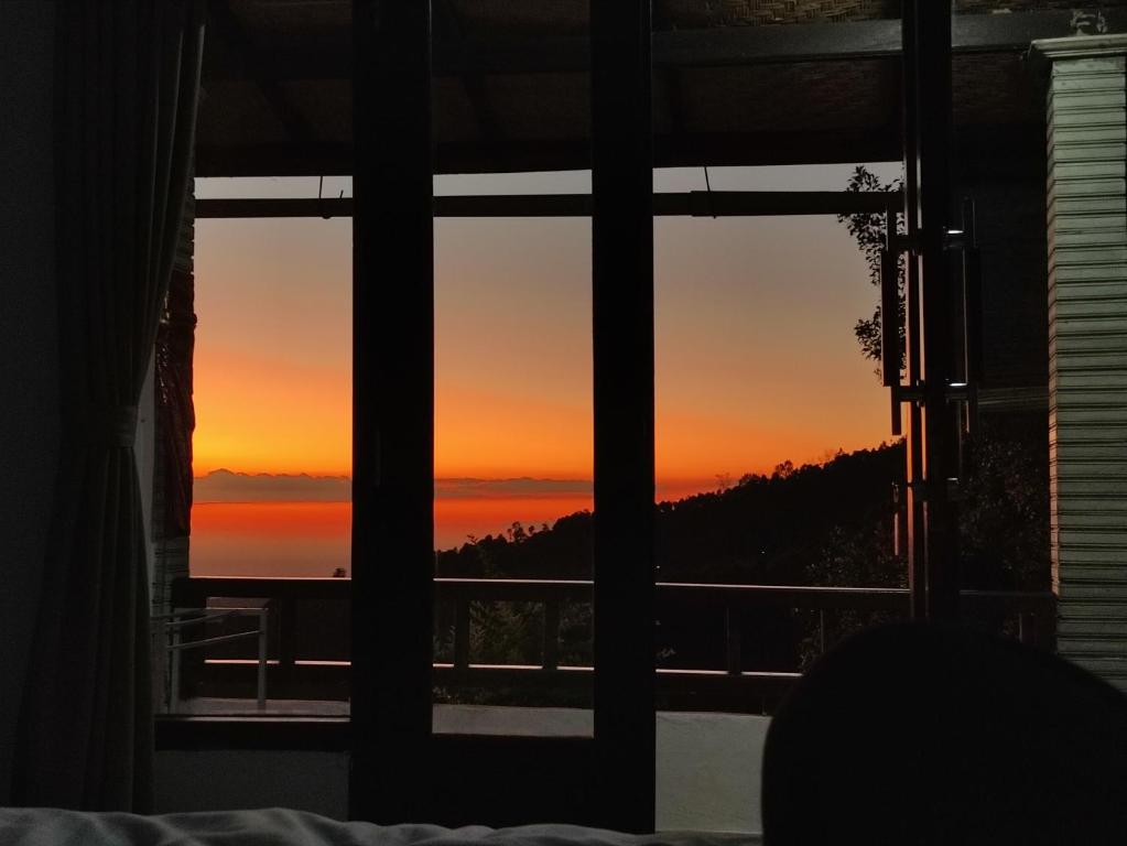 Puri Sunset Homestay في موندوك: إطلالة على غروب الشمس من نافذة غرفة النوم