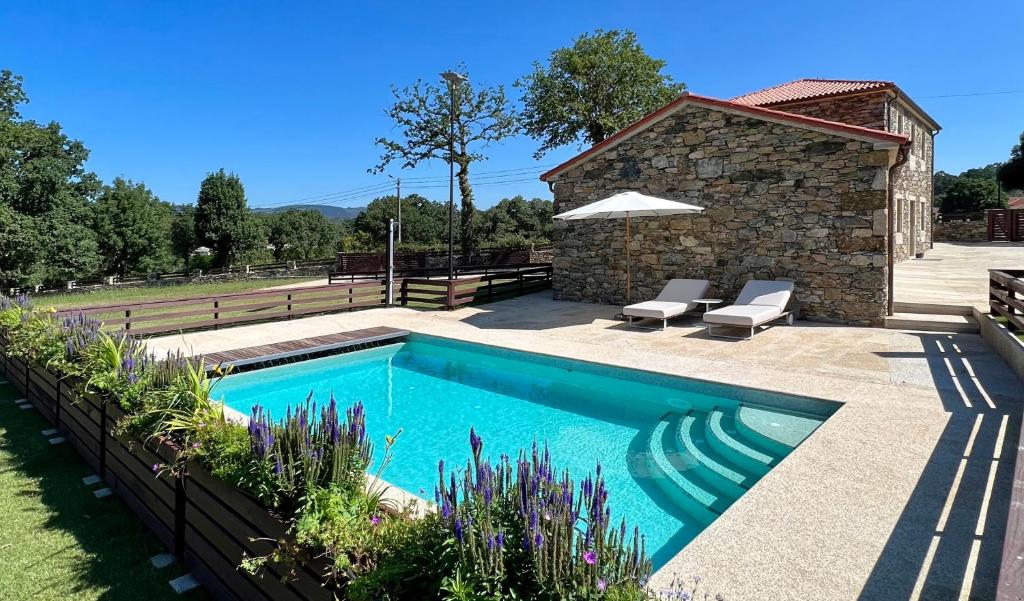 a swimming pool in a yard with a stone building at Casa do Gaiteiro 