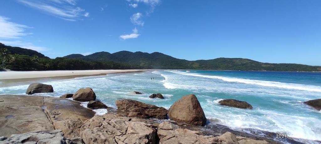 a beach with rocks in the water and mountains at Bela Casa Quartos e Hostel Ilha Grande in Abraão