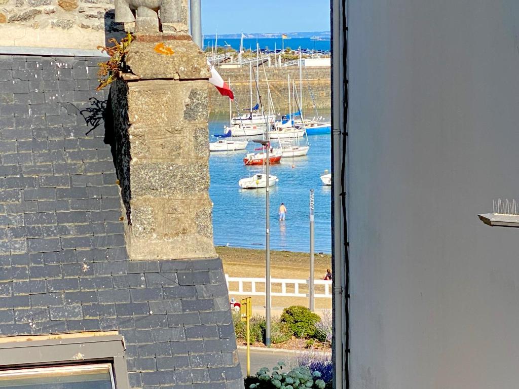 een uitzicht op een haven vanuit een raam van een gebouw bij Saint-Quay-Portrieux Grande Maison avec terrasse à 40m de la plage du port in Saint-Quay-Portrieux