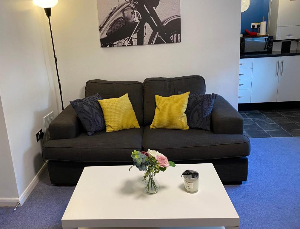 a living room with a couch with yellow pillows and a table at 1 bedroom apartment with own entrance and parking space in Huntingdon