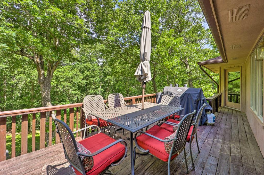 una mesa y sillas en una terraza con sombrilla en Lakefront Getaway with Private Dock and Kayaks!, en Bella Vista