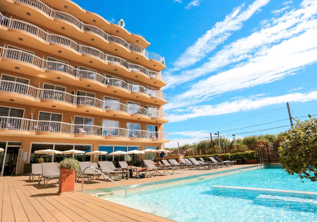 um hotel com piscina e cadeiras e um edifício em KAKTUS Hotel Volga - Adults Recommended em Calella