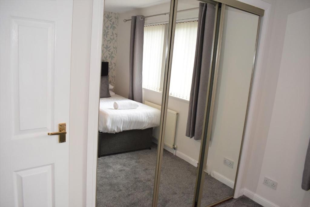 a mirror in a room with a bed and a window at Kelpies Serviced Apartments- McLaughlan in Falkirk