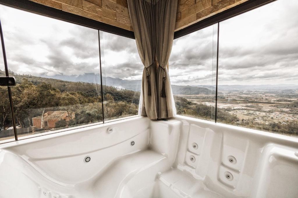 a bath tub in a room with large windows at Discovery Canyon in Praia Grande