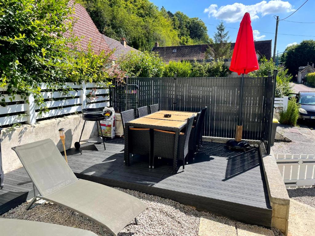 una terraza de madera con mesa, sillas y sombrilla roja en Agréable maison 3* en bord de mer, en Dieppe