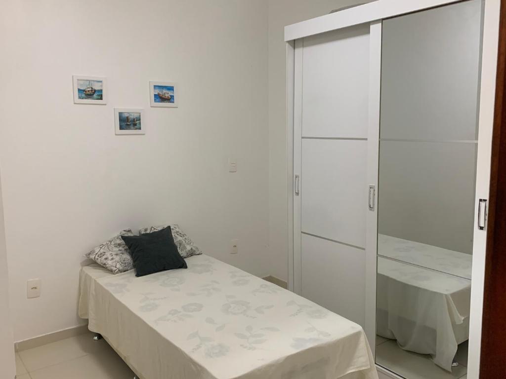 a white bedroom with a bed and a closet at Apê de Mainha in Ilhéus