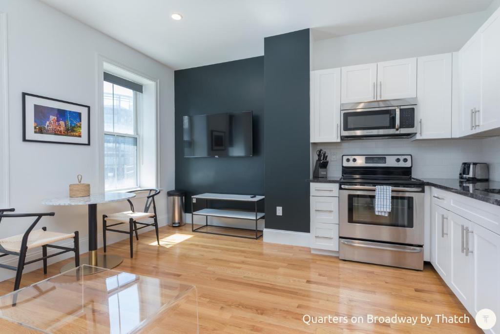 a kitchen with white cabinets and a table with chairs at West Broadway Quarters by Thatch in Boston