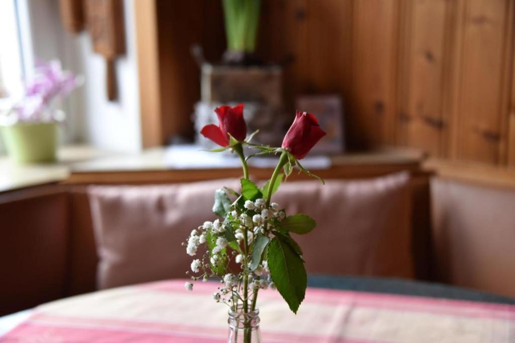 a vase with three roses in it on a table at Landgasthof Grüner Baum in Regnitzlosau