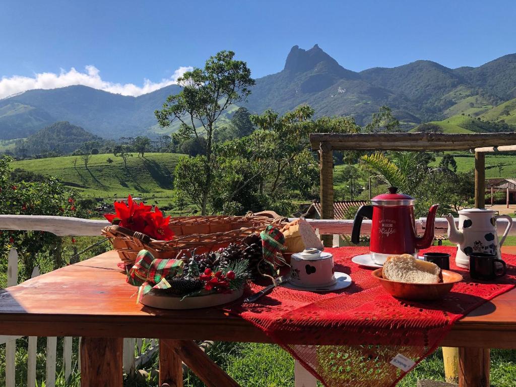 a picnic table with a basket of food on it with mountains at Chalé jeito de roça na Pedra Selada in Visconde De Maua