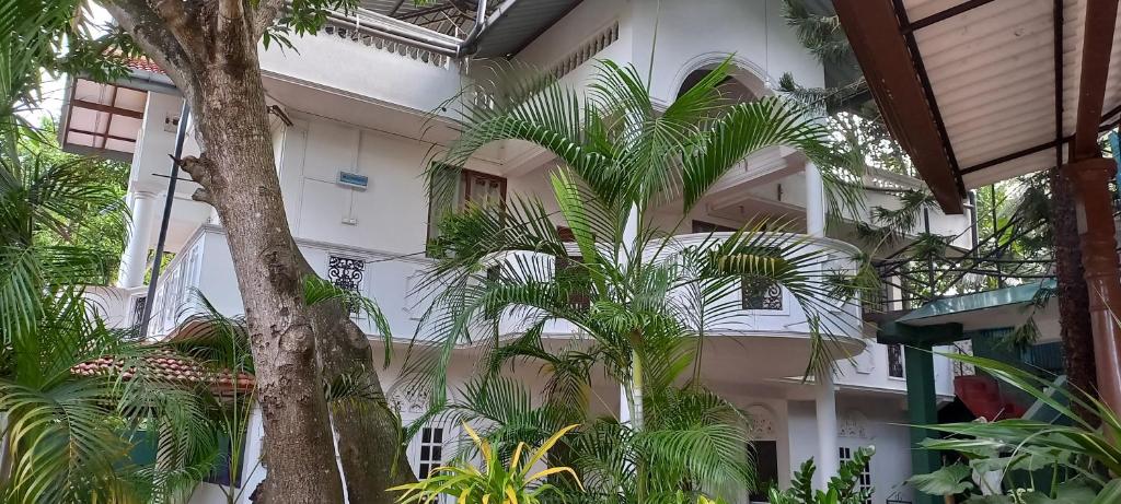 a white building with palm trees in front of it at Shady transit hotel in Katunayake