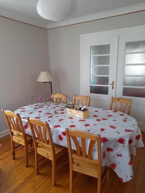 une table à manger avec un tissu de table blanc et des fleurs rouges dans l'établissement Apigîte68, proche route des vins, Vosges, Colmar et non loin d'Europa-Park!, à Ostheim