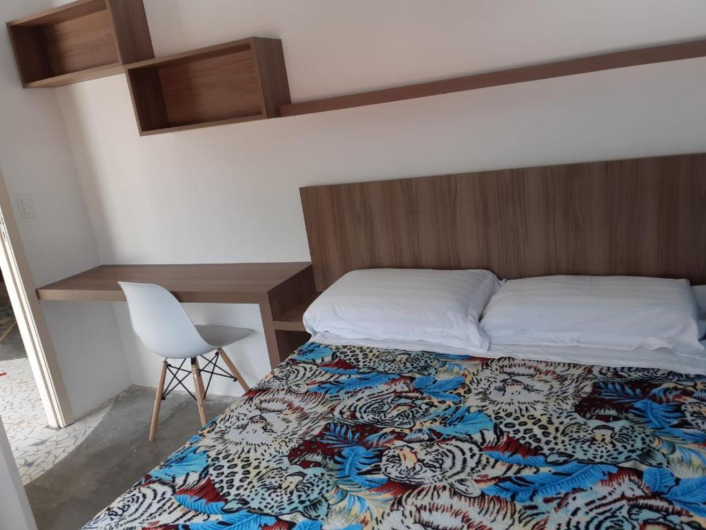 1 dormitorio con cama, silla y escritorio en Varanda_77, en São Paulo