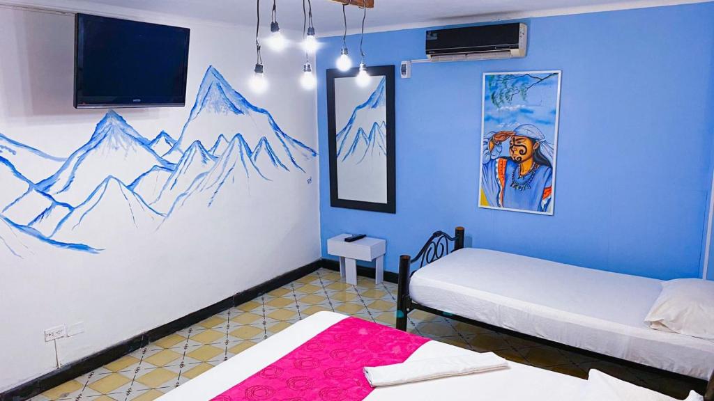 a room with two beds and a painting on the wall at Hotel El Exito in Santa Marta