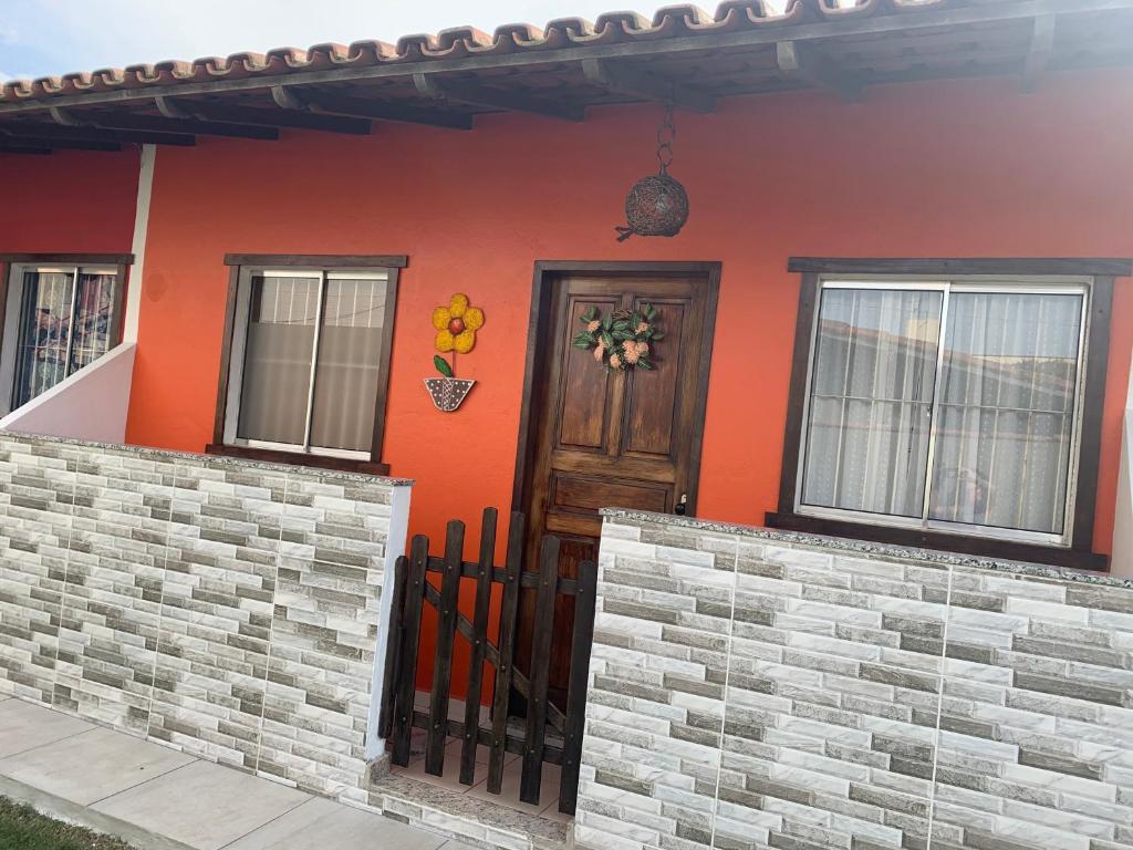 uma casa com uma parede laranja e uma porta de madeira em Chalé beira mar Jacaraipe em Serra