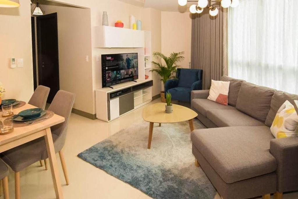 ein Wohnzimmer mit einem Sofa und einem TV in der Unterkunft Holiday suite at Uptown Parksuites II Uptown BGC in Manila