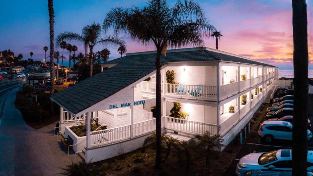 a white house with a palm tree in front of it at Del Mar Beach Hotel in San Diego