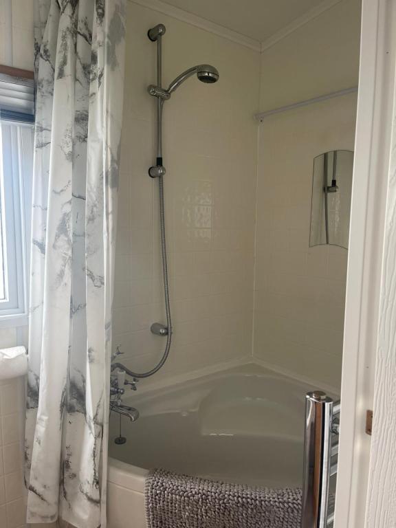 a bathroom with a bath tub with a shower curtain at Immaculate 2-Bed Lodge in Monreith in Newton Stewart