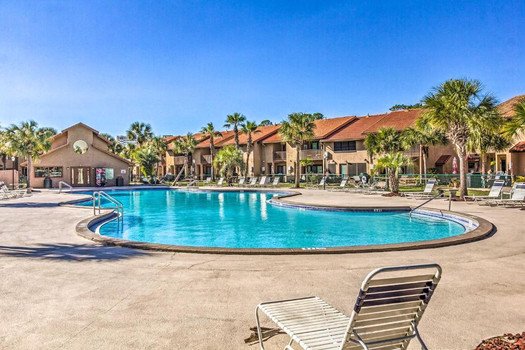 einen Pool in einem Resort mit Stühlen und Palmen in der Unterkunft Updated PCB Resort Townhome - Walk to Beach! in Panama City Beach