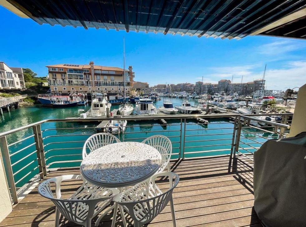a table and chairs on a balcony with a marina at ShipsBell 5B in St Francis Bay
