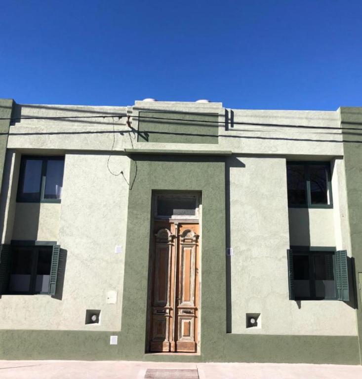 a green and white building with a wooden door at Azul en Lavalle 4 in Azul