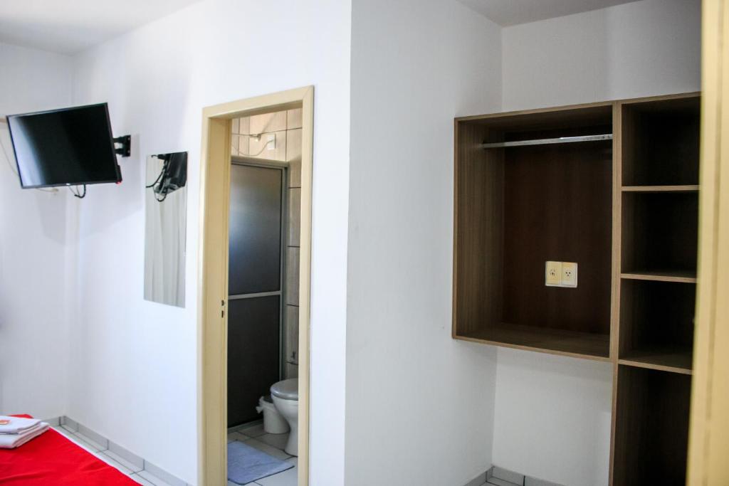 een badkamer met een toilet en een tv aan de muur bij Hotel Palugi in Joinville
