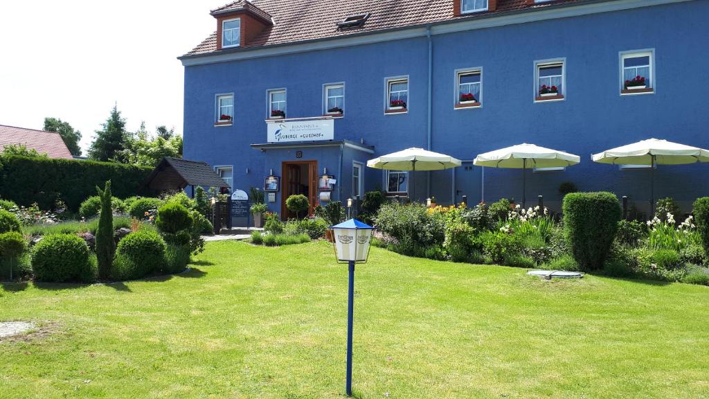 a blue building with umbrellas and a light in the grass at Logis L Auberge Gutshof in Bischofswerda