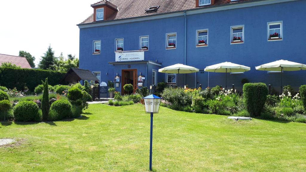 un bâtiment bleu avec des parasols et une lumière dans l'herbe dans l'établissement Logis L Auberge Gutshof, à Bischofswerda