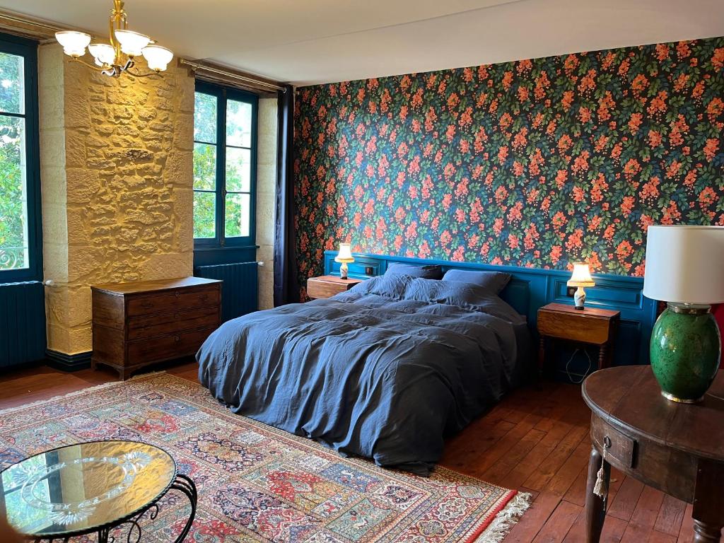 a bedroom with a bed and a floral wall at Le Clos Chalmon Chambre d'hôte in Montignac