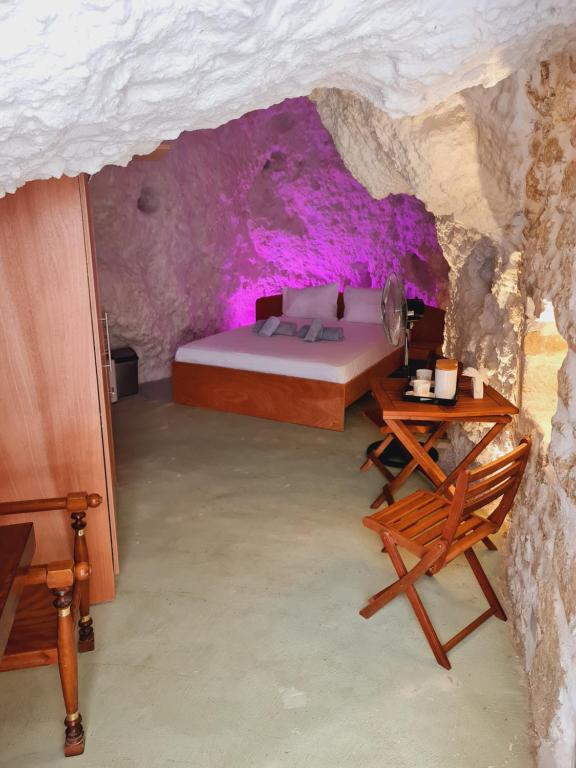ein Schlafzimmer mit einem Bett und einem Tisch in einer Höhle in der Unterkunft Anassa Cave by Estia in Iraklio