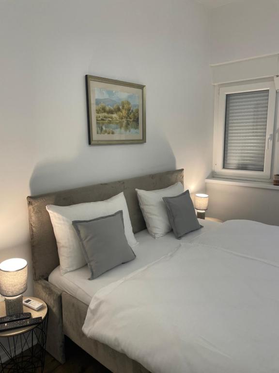 1 dormitorio con 1 cama grande con sábanas y almohadas blancas en Luxury Apartment in Sarajevo, en Sarajevo