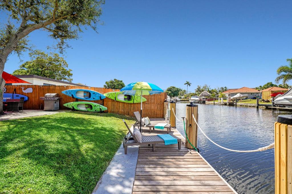 a wooden dock with a table and chairs next to a river at Waterfront Fll&beaches, Bbq, Kayaks, Canoe in Dania Beach