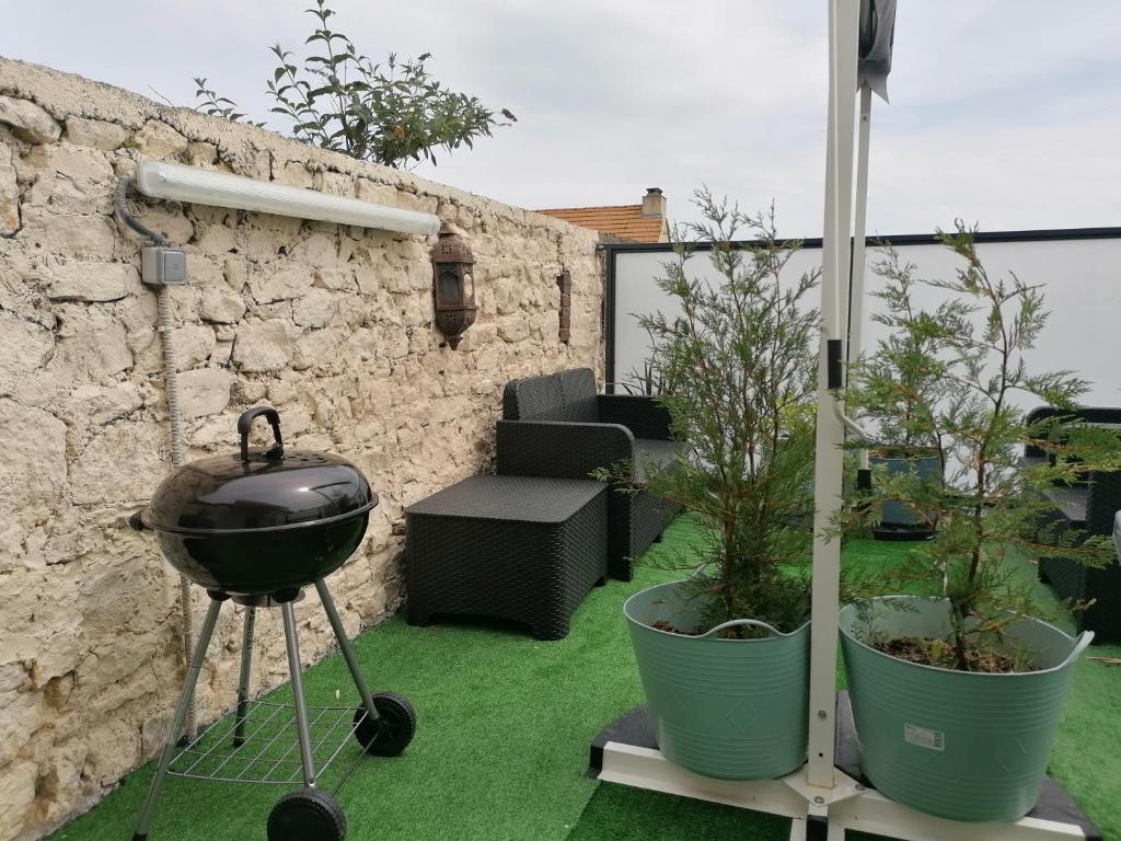 a grill on a stand next to two potted plants at Apt duplex spacieux 4 chambres belle terrasse aménagée près Omaha Beach et Bayeux 800 m plage et 300 m superette in Vierville-sur-Mer