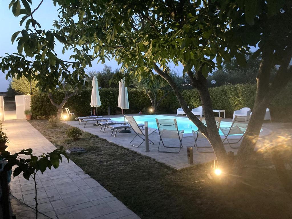 a pool with chairs and umbrellas next to a tree at Villa Mater in Matera