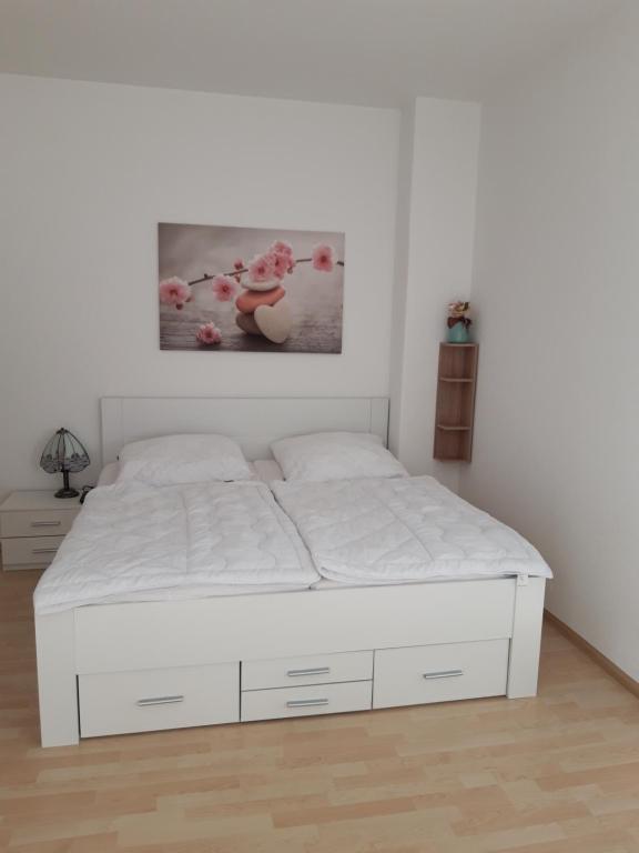 a white bed in a bedroom with a white wall at gemütliche kleine Ferienwohnung in Chemnitz