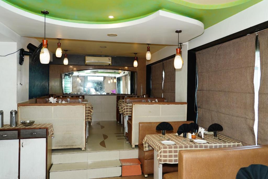 a restaurant with tables and chairs and a green ceiling at Marshall The Hotel in Ahmedabad