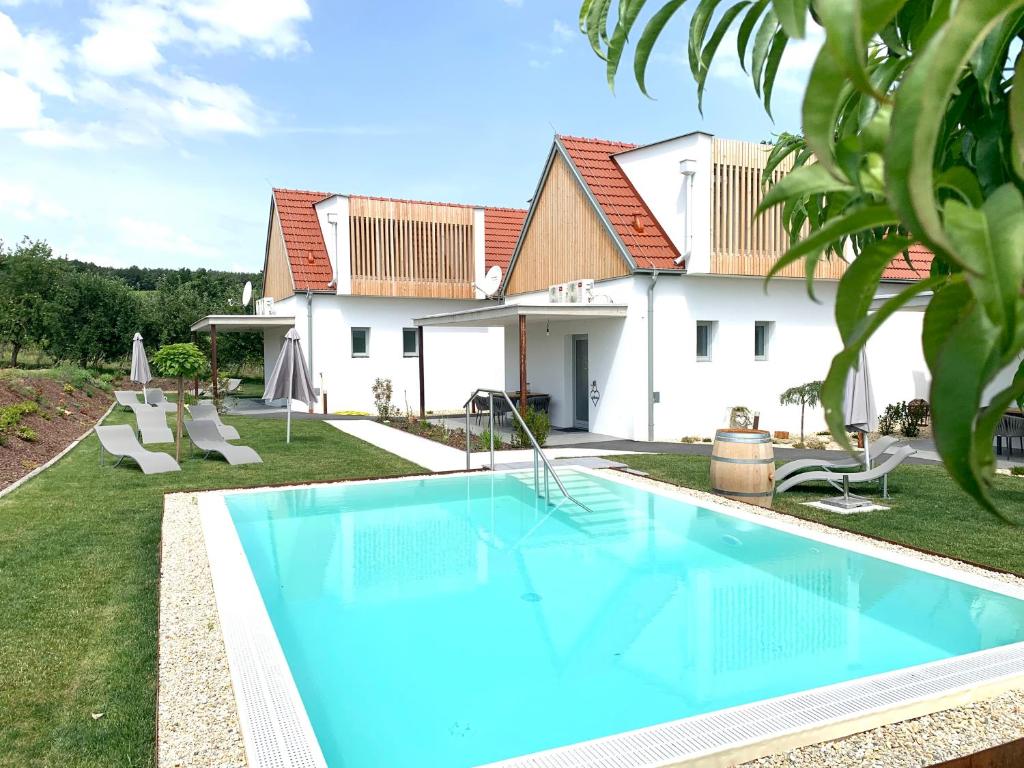 a villa with a swimming pool in front of a house at Weinberg Chalets in Eisenberg an der Pinka