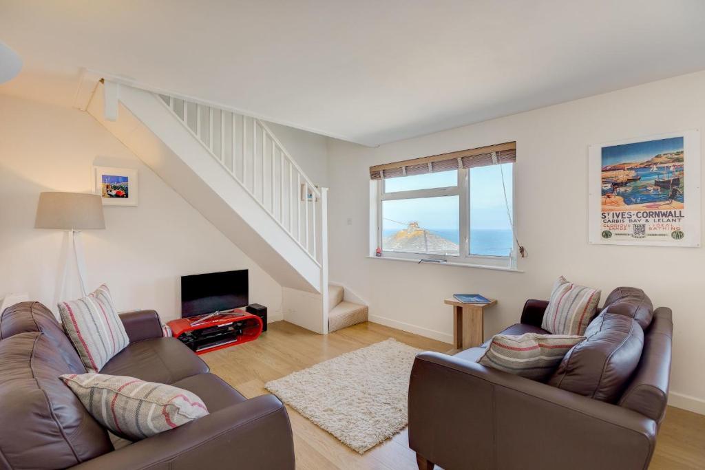 a living room with two couches and a staircase at Atlantic Blue in Carbis Bay