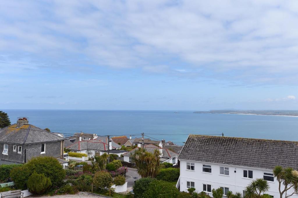 a town with houses and the ocean in the background at St Ives Bay View in Carbis Bay