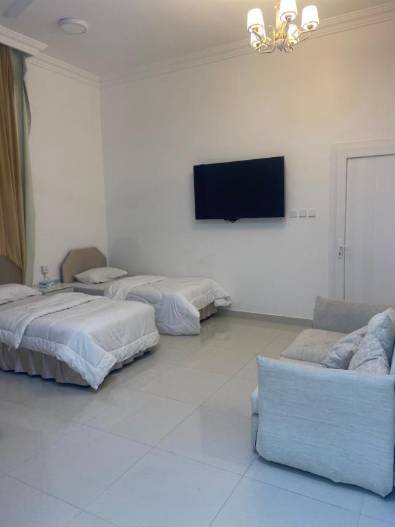 um quarto com 3 camas e uma televisão de ecrã plano em Almouj Chalet em Salalah