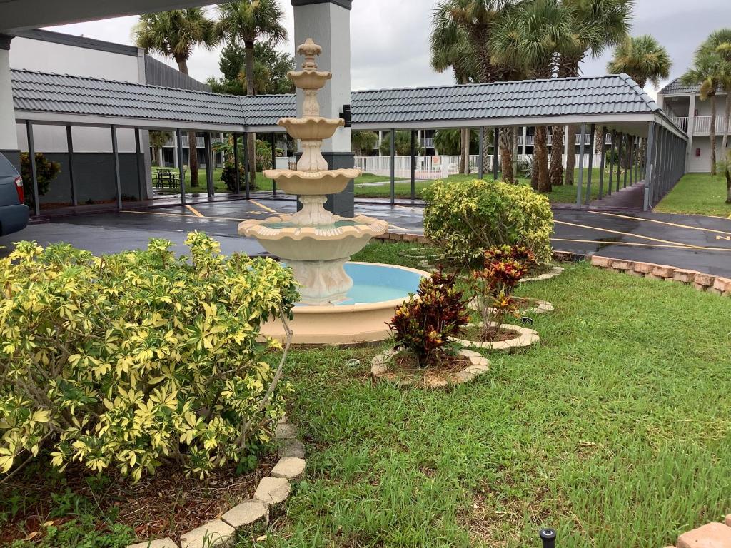 einen Brunnen inmitten eines Gartens mit Büschen in der Unterkunft Heritage Park Inn in Kissimmee