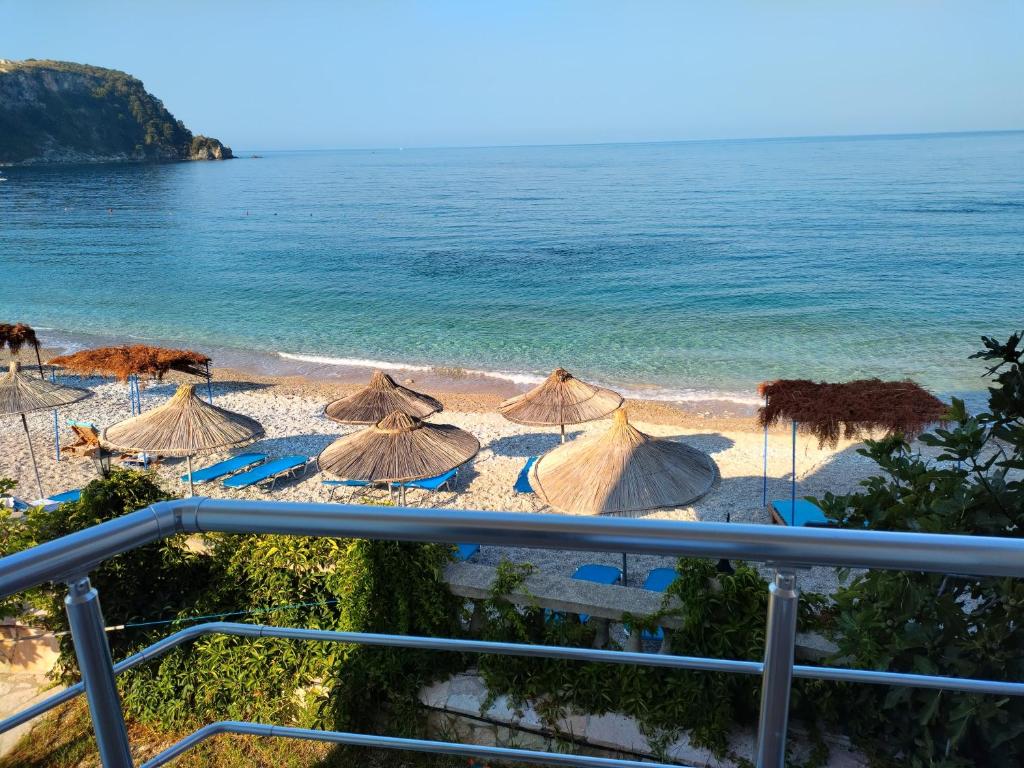 un grupo de sombrillas en una playa con el océano en Magic Ionian Apartments & Rooms, en Himare