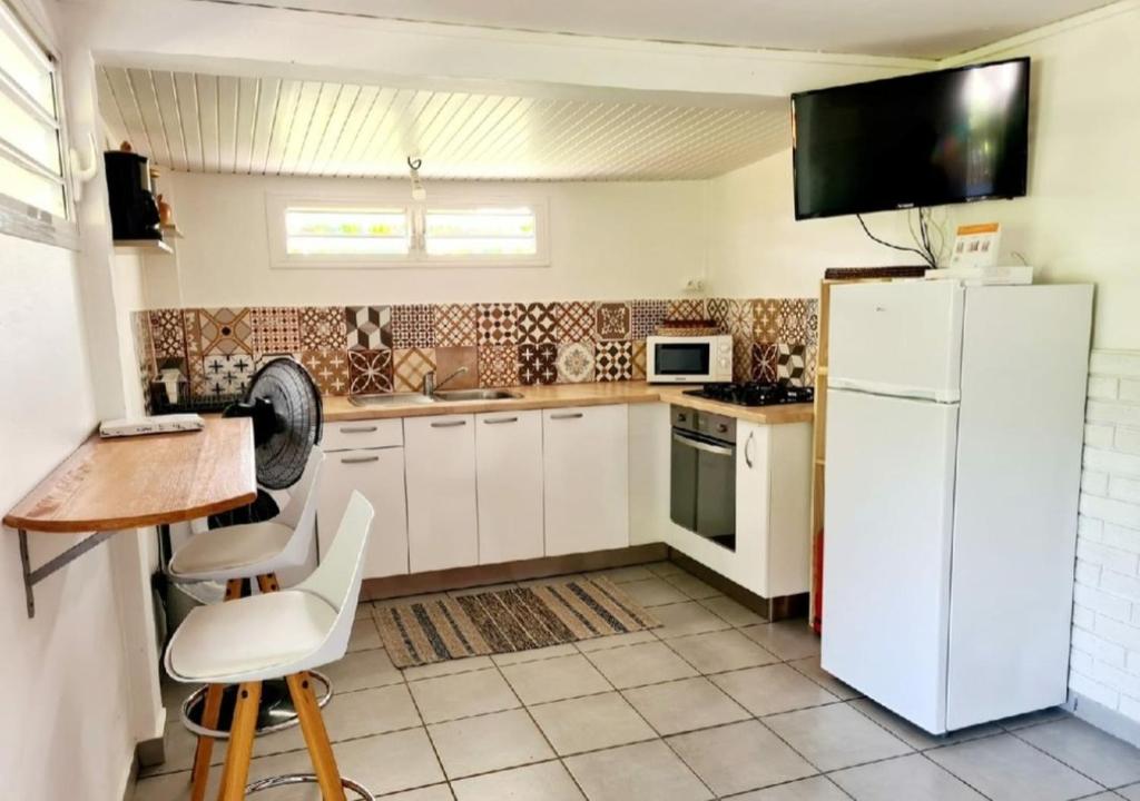 勒弗朗索瓦的住宿－A l'ombre du goyavier，厨房配有白色冰箱、桌子和椅子