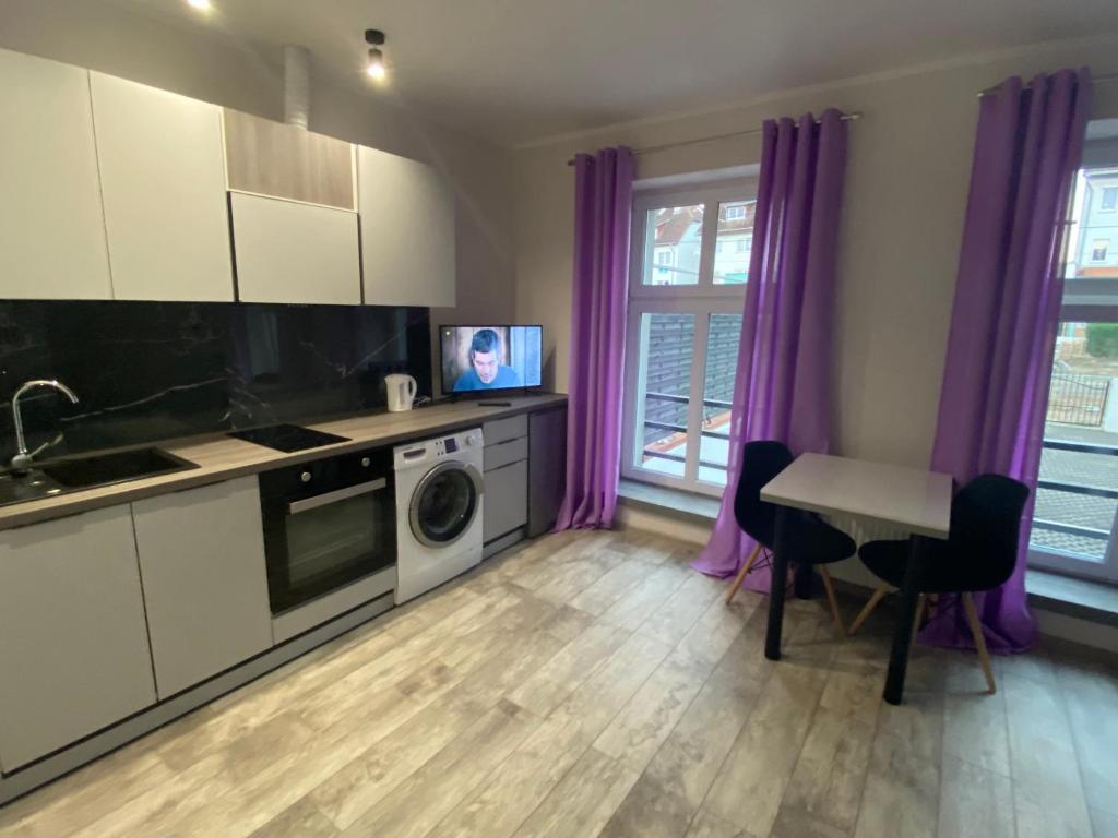 a kitchen with purple curtains and a table and a microwave at Apartamenty Bezrzecze in Szczecin