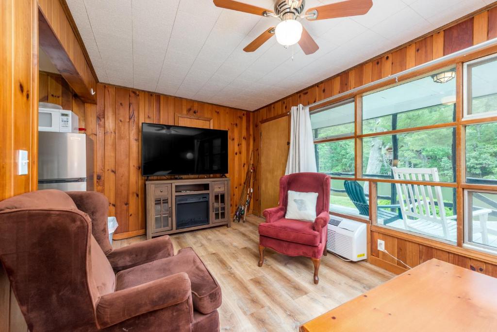 ein Wohnzimmer mit einem Deckenventilator und einem TV in der Unterkunft Lakeside Delight - Unit 302 in Flat Rock