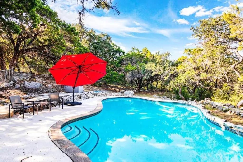 a swimming pool with a red umbrella and a table and chairs at Salt Water Pool & Backyard Oasis @ Wild Eagle in San Antonio