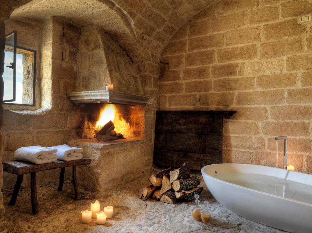 a stone bathroom with a tub and a fireplace at Sextantio Le Grotte Della Civita in Matera