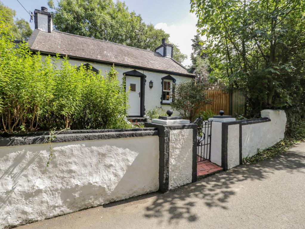 a white house with a fence in front of it at Carreg Winllan in Amlwch