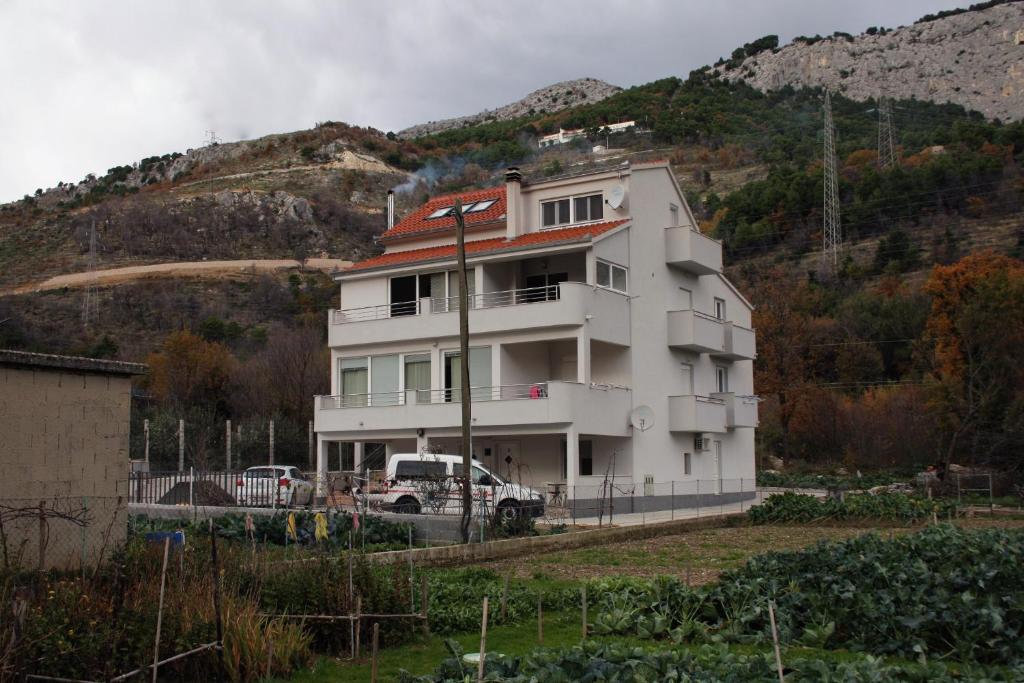 een wit huis met een vrachtwagen er voor geparkeerd bij Apartments with a swimming pool Zakucac, Omis - 5954 in Omiš