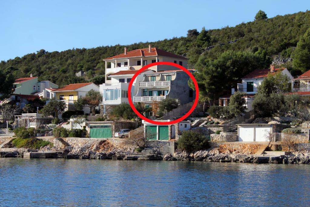 ein Haus mit einem roten Kreis neben dem Wasser in der Unterkunft Apartments by the sea Vinisce, Trogir - 5981 in Vinišće